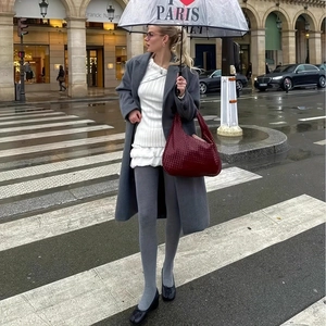 Deep burgundy woven leather hobo bag held by a model on a stylish European street
