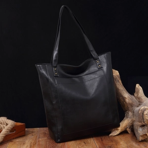Détail du sac cabas en cuir noir avec poche avant et finitions en rivets métalliques
