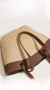 Close-up of woven straw texture and premium brown leather handle on a beach tote bag
