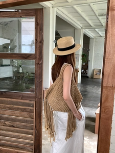 Dettaglio borsa a tracolla intrecciata con frange fatta a mano, ideale per vacanze al mare.