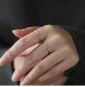 Macro detail of slim gold titanium ring featuring a delicate zircon stone on hand