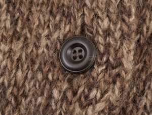 Close-up of brown chunky cable knit texture with a matte four-hole button detail