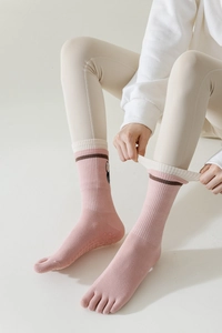 Close-up of pink five-toe yoga socks with anti-slip grips and stylish color-block cuffs