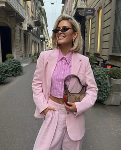 Détail d'une chemise courte à rayures roses avec un blazer rose assorti et un pantalon fluide
