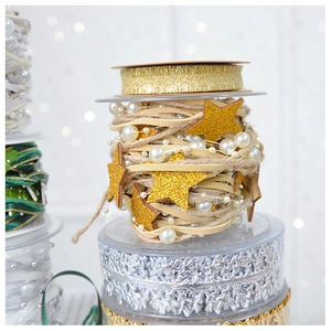 Detail of Christmas ribbon rolls with gold stars, pearls, and pink bow for gift wrapping