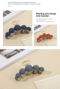 Detail of matte spherical hair claws in navy blue, brick red, and grey finishes