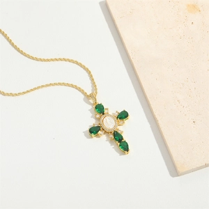 Gold cross necklace with green teardrop gemstones and white icon relief on stone base