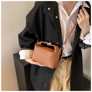 Brown woven leather shoulder bag styled as a crossbody on a model in a minimal setting