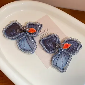 Handmade blue beaded butterfly hair clips with pearl embroidery in a ceramic tray