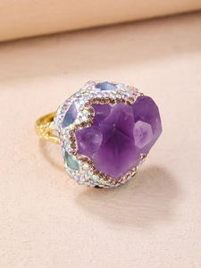 Détail macro d'une bague avec grappe de cristal violet, strass et texture dorée ciselée