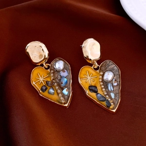 Detail view of heart earring with baroque pearl and star pattern on silk fabric