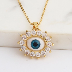 Close-up of gold Evil Eye necklace with micro-pave zircons on white marble background