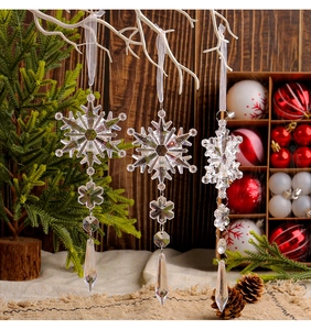 Detailed view of three acrylic crystal snowflake ornaments hanging with silk ribbons