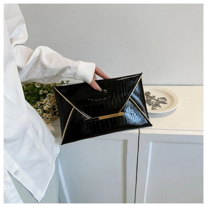Detail of elegant black crocodile embossed envelope clutch with luxury gold buckle detail