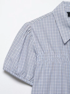 Detail of blue and white plaid shirt featuring puff sleeve stitching and sharp collar design