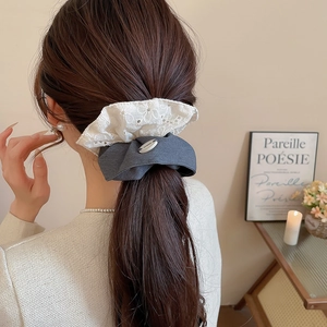 Vue détaillée d'un chouchou noeud géant en dentelle et tissu gris sur cheveux de femme