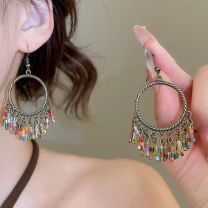 Detail of vintage flower earrings with bronze twisted rings and colorful seed bead tassels