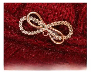 Detail of rose gold bow brooch with inlaid rhinestones on a thick red knit winter hat