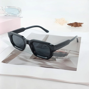 Classic thick frame square sunglasses with black frames and dark lenses on a magazine
