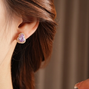Macro shot of elegant rose gold pear-shaped earrings with lavender stone on model