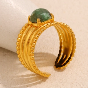 Macro shot of 18K gold plated ring with emerald stone and wavy texture band