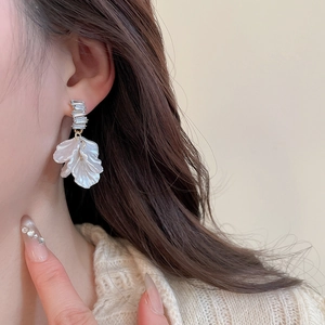 Dettaglio di un orecchino a fiore con perle e cristalli chiari su una modella