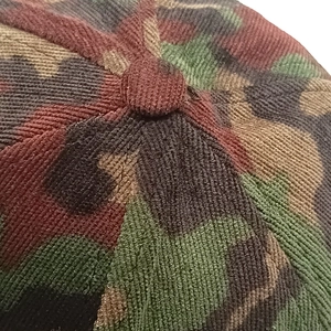 Detailed macro view showing camouflage corduroy texture and top button on baseball cap