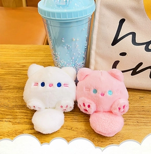 Dettaglio di portachiavi a gatto in peluche bianco e rosa con simpatiche espressioni ricamate