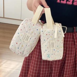 Detailed macro view of white quilted vanity bags with colorful dots and bow accents