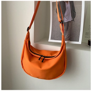 Bright orange crescent nylon crossbody bag hanging against a minimalist gray wall niche