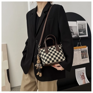Détail du sac cabas à carreaux avec poignées en cuir et pendentif lapin sur mannequin