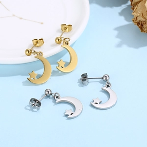 Detailed view of gold and silver moon and star stud earrings on a decorative plate