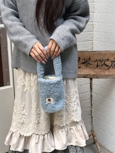 Close-up of light blue plush handbag with fluffy texture and cute cartoon patch detail