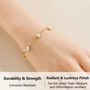 Detail of gold bracelet with white heart charms on wrist against silk background