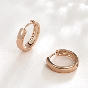 Dettaglio di orecchini a cerchio minimalisti in oro rosa con finitura lucida a specchio