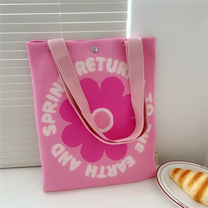 Close-up of pink knitted tote bag showing magnetic buckle and floral print detail