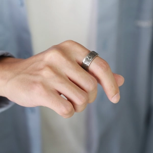 Detail of rotating stainless steel cross ring with Lord's Prayer engraving on hand