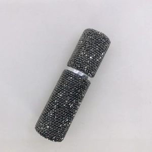 Macro view of refillable perfume bottle with sparkling dark grey rhinestones surface