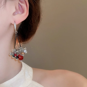 Détail de boucles d'oreilles à pompons avec perles en zircon sur un modèle de profil