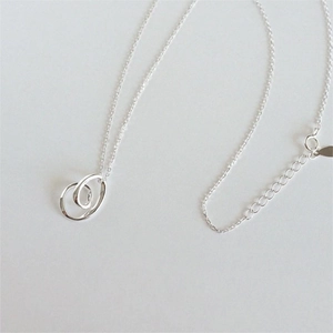 Close-up of a 925 sterling silver necklace featuring a double spiral intertwined pendant