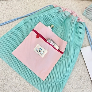 Détail du sac à cordon en filet vert menthe avec poche rose et capacité de stockage