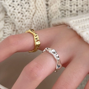 Detailed view of gold and silver irregular lava rings on fingers with a knit sweater background