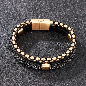 Close-up of golden magnetic clasp and black braided leather layers on men's bracelet