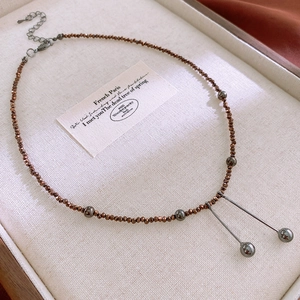 Detail of retro natural stone necklace with brown beads and metallic pendants on display