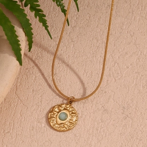 Macro detail of 18K gold plated snake chain with amazonite coin pendant and leaf accent
