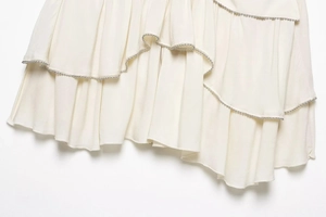 Detailed view of layered cream ruffles with silver bead trim on a women's skirt