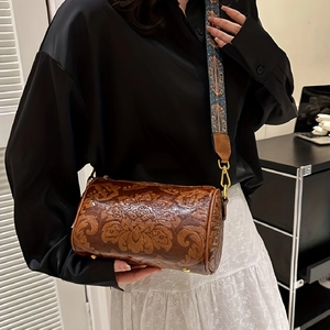 Detail of vintage brown cylinder bag with floral embossing and embroidered wide strap