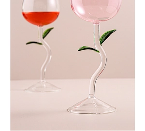 Detailed close-up of rose flower shaped red wine glasses with green stem and leaf design