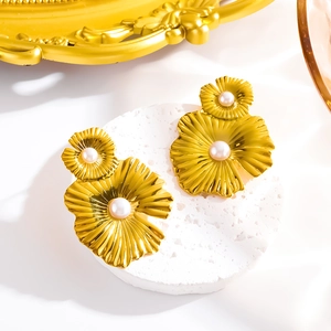 Elegant gold flower petal drop earrings with pearls on a white stone pedestal
