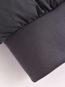 Détail de la veste courte gris foncé montrant les poignets en maille et le tissu coupe-vent